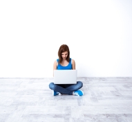 Young beautiful woman sitting at the floor and using laptop